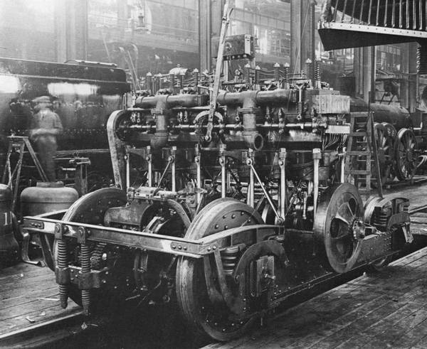 The McKeen motor car's 6-cylinder overhead-valve gasoline engine was a source constant irritation to the V&T's motormen and mechanics. It was hard to start and so rough-running that it required a massive flywheel at the end of the crankshaft to keep it from stalling. In order to reverse the direction the car moved in the engine first had to be shut down, after which the tall lever protruding from the upper center of the engine -- connected to two sliding camshafts on either side of the engine, each with two sets of cams -- had to be moved. This changed the valve timing , so that when restarted the engine would then rotate in the opposite direction. --- Editor